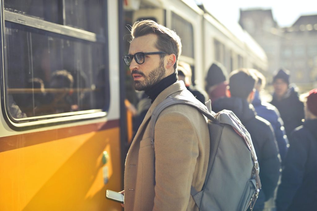 man-in-brown-coat-and-gray-backpack-posing-for-a-photo